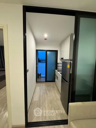 Modern kitchen with sleek design and balcony view, featuring a fridge and ample storage space.