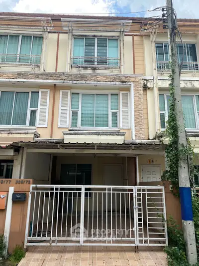 Charming three-story townhouse with gated entrance and modern facade, perfect for urban living.