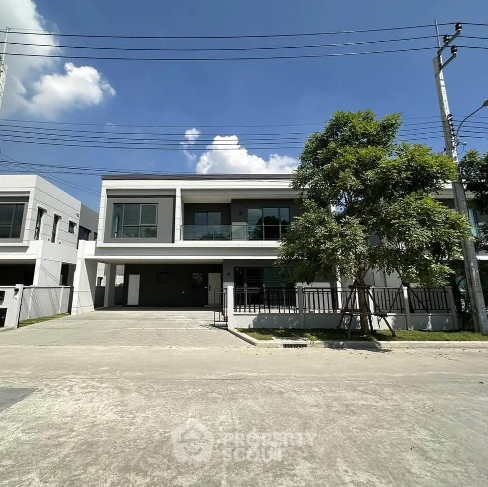 Modern two-story house with large windows and driveway in a suburban neighborhood.