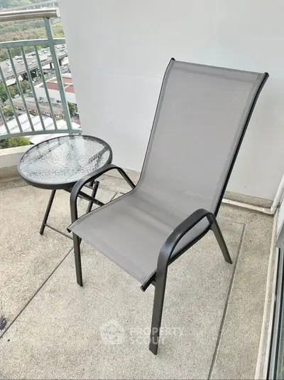 Chic balcony with modern chair and glass table offering serene views.
