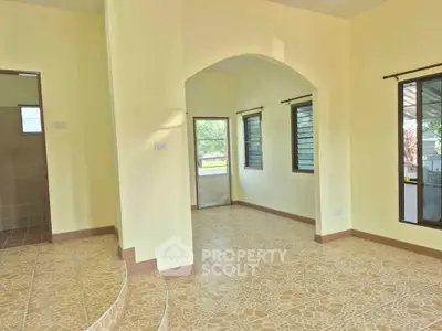 Spacious interior with tiled floors and large windows in a bright, airy home.
