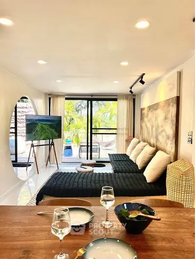 Stylish living room with modern decor and large windows overlooking lush greenery.