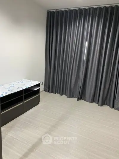 Spacious room with elegant gray curtains and modern flooring, perfect for versatile interior design.