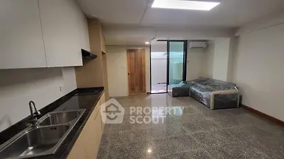 Modern open-plan living room with sleek kitchen and cozy seating area, perfect for urban living.