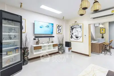 Modern living room with stylish decor and open layout, featuring a large fridge and wall art.