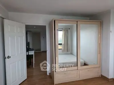 Spacious bedroom with wooden flooring and mirrored wardrobe