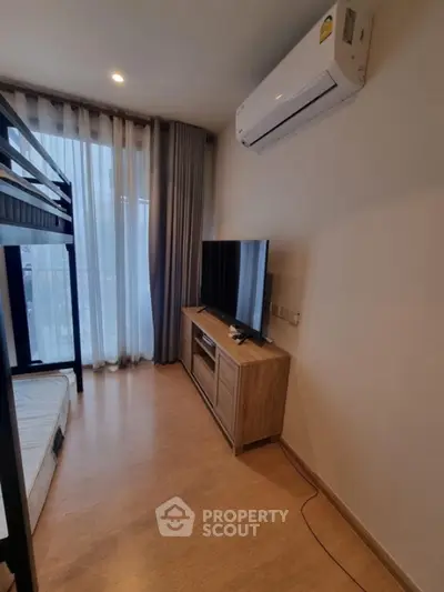 Modern bedroom with bunk bed, TV, and air conditioning in a cozy apartment.