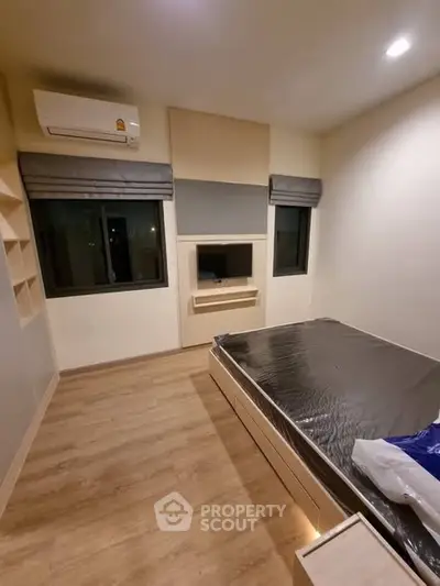 Modern bedroom with wooden flooring and built-in storage solutions.