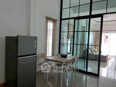 Modern open-plan kitchen and living area with sleek glass partition and natural light.