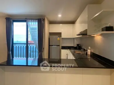 Modern kitchen with sleek design and balcony view, featuring open layout and contemporary appliances.