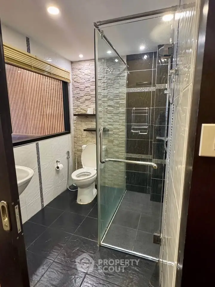 Modern bathroom with glass shower and stone accent wall