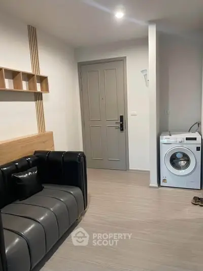 Modern apartment interior with stylish sofa and washing machine near entrance.