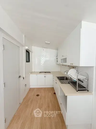 Sleek modern kitchen with white cabinetry and wooden flooring, perfect for culinary enthusiasts.