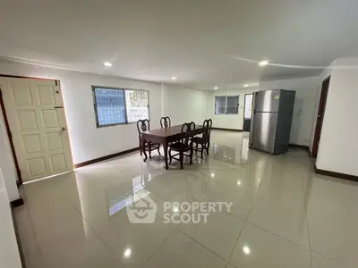 Spacious open-plan living area with dining set and modern refrigerator, perfect for family gatherings.