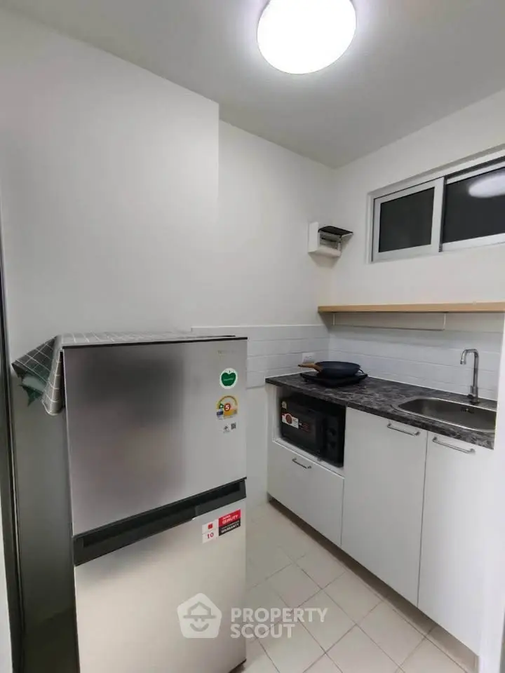 Modern compact kitchen with stainless steel fridge and sleek cabinetry