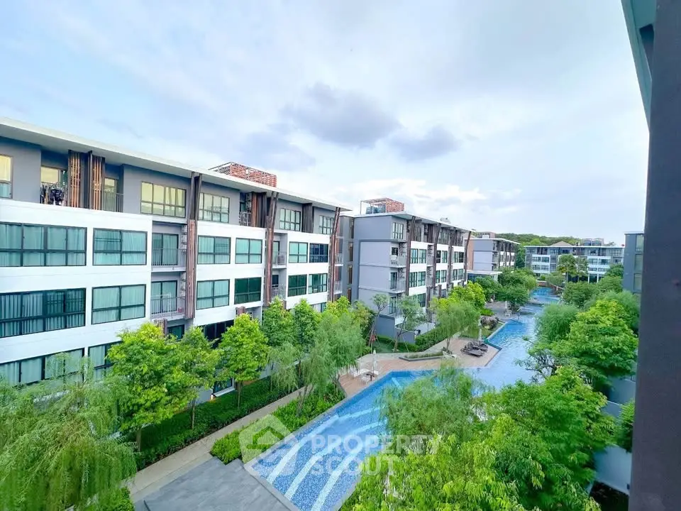 Modern condominium complex with lush gardens and a serene pool view.