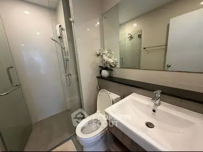 Modern bathroom with glass shower, sleek sink, and elegant decor in a contemporary home.