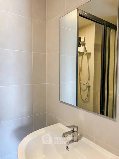 Modern bathroom with sleek sink and mirror, featuring a shower enclosure.