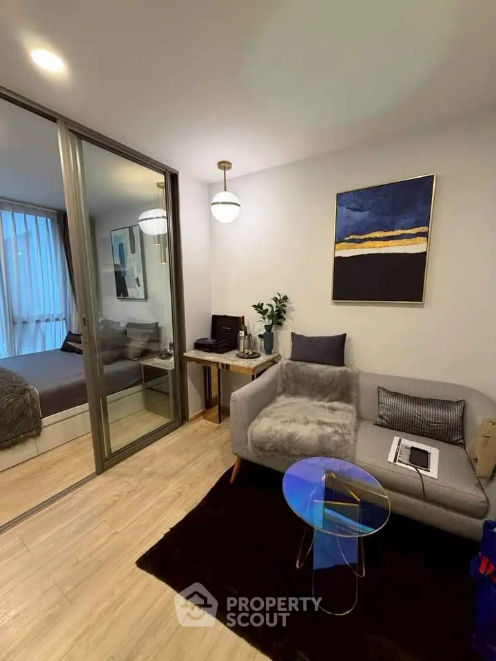 Modern living room with cozy decor and adjacent bedroom, featuring stylish furniture and elegant lighting.