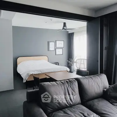 Modern bedroom with stylish decor and cozy seating area, featuring natural light and elegant furnishings.