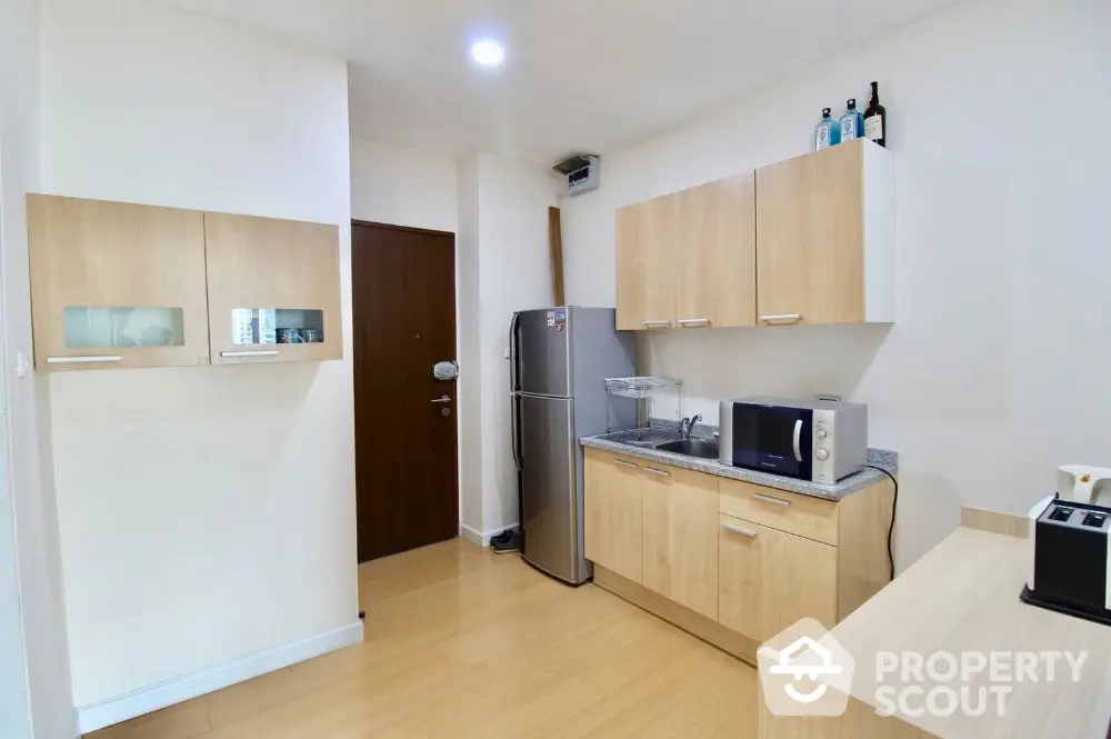 Modern kitchen with wooden cabinets and stainless steel appliances in a cozy apartment.