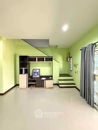 Spacious living room with modern staircase and bright green walls