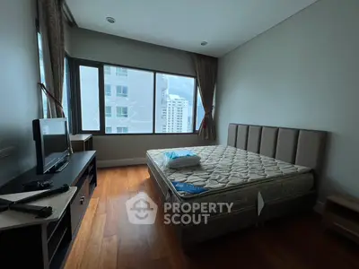 Spacious bedroom with large windows and wooden flooring in modern apartment
