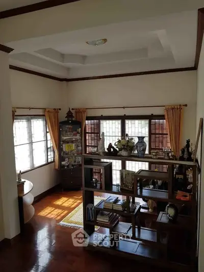 Charming living room with elegant wooden shelves and large windows, offering a cozy and inviting atmosphere.