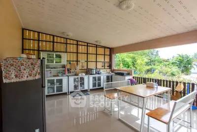 Spacious outdoor kitchen with dining area and lush garden view, perfect for entertaining and family gatherings.
