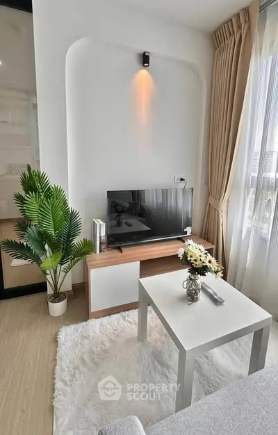 Modern living room with cozy decor, featuring a TV, stylish furniture, and elegant curtains.