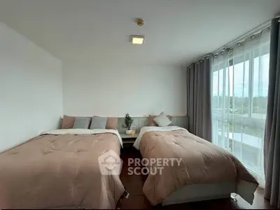 Spacious bedroom with two beds and large windows offering natural light and scenic views.