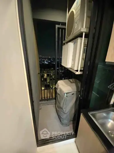 Compact balcony with city view, air conditioning units, and laundry area in modern apartment.