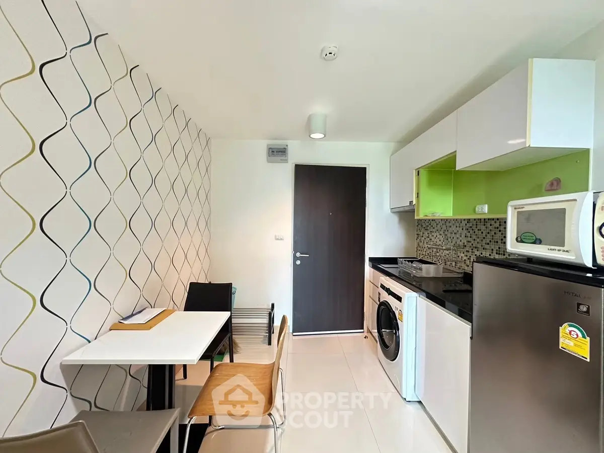 Modern kitchen with dining area, featuring washing machine and sleek appliances.