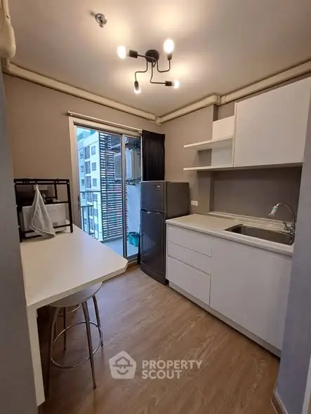 Modern compact kitchen with sleek cabinetry and balcony access