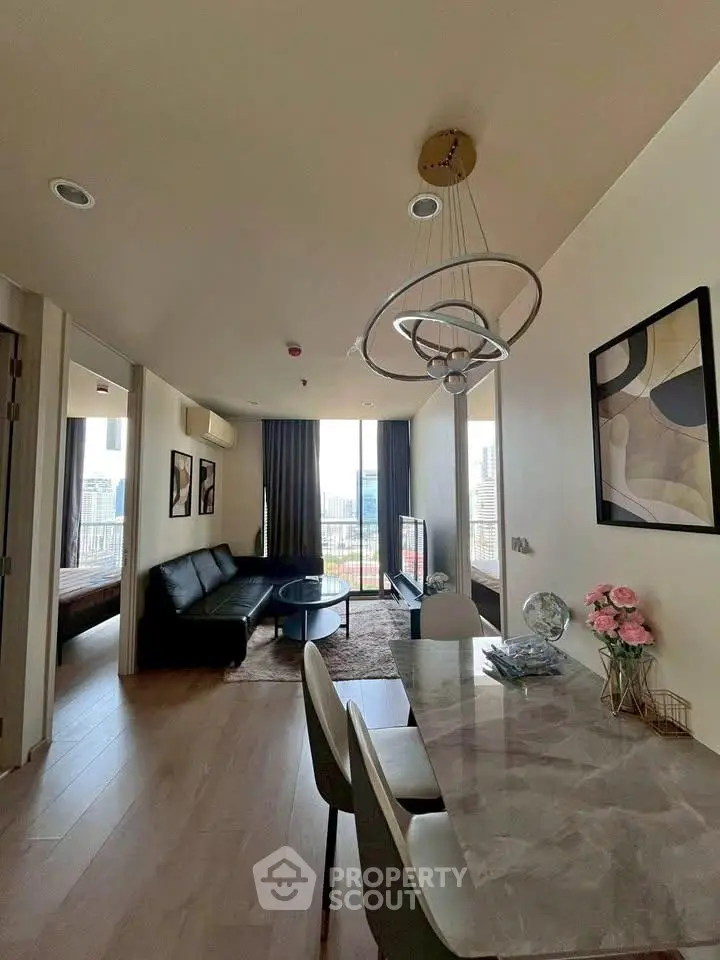Modern living room with city view, stylish decor, and elegant dining area in a high-rise apartment.