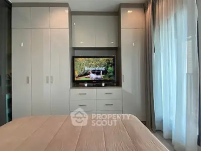 Modern bedroom with built-in wardrobe and TV, featuring elegant curtains and cozy bedding.