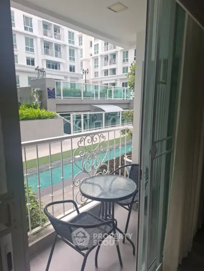 Charming balcony view overlooking pool in modern apartment complex, perfect for relaxation and leisure.