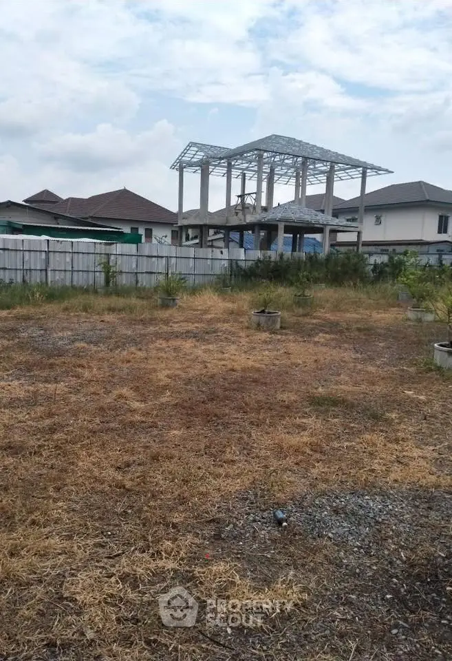Vacant land with partial construction and residential backdrop, ideal for development.