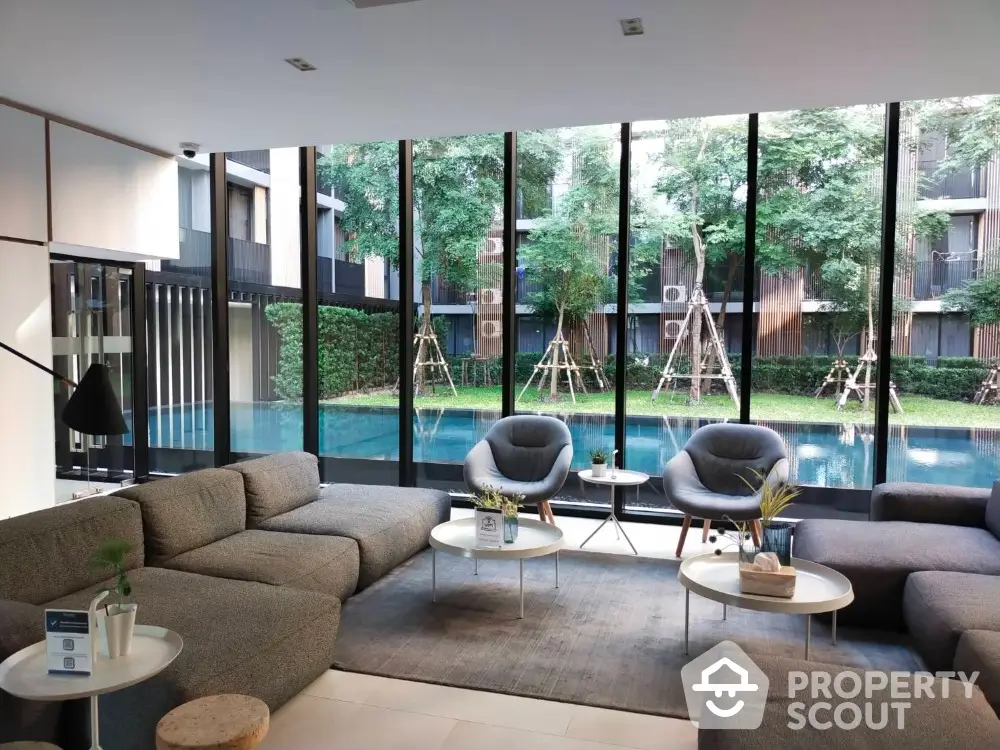 Luxurious living room with floor-to-ceiling windows overlooking a serene pool and landscaped garden, featuring plush seating and modern decor.