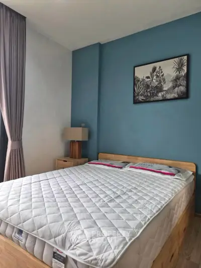 Cozy bedroom with stylish decor and natural light, featuring a comfortable bed and elegant curtains.