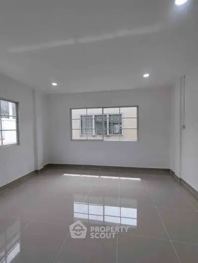 Spacious empty room with large windows and glossy tiled floor, ideal for customization.