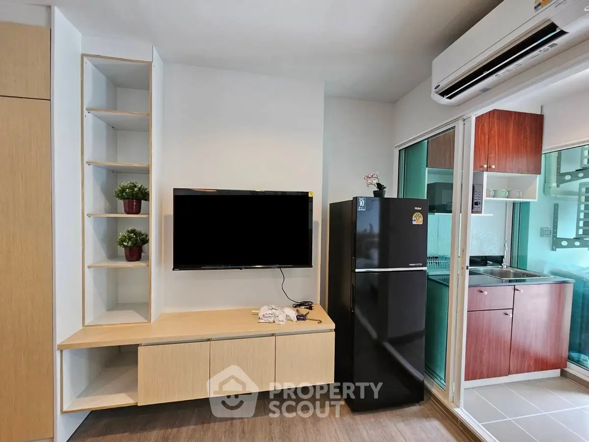 Modern living room with sleek TV setup and compact kitchen area