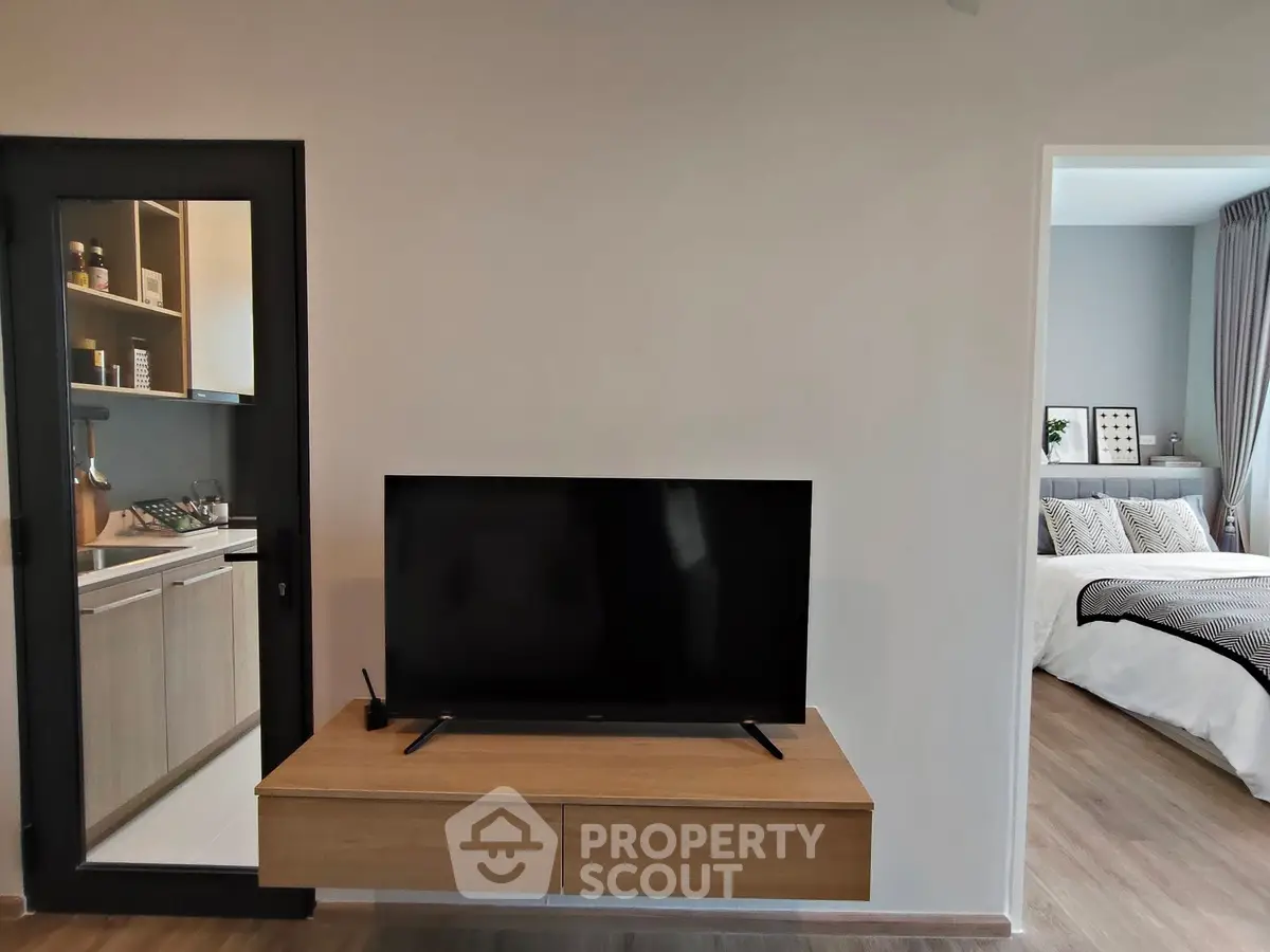 Modern living room with wall-mounted TV and view into stylish bedroom