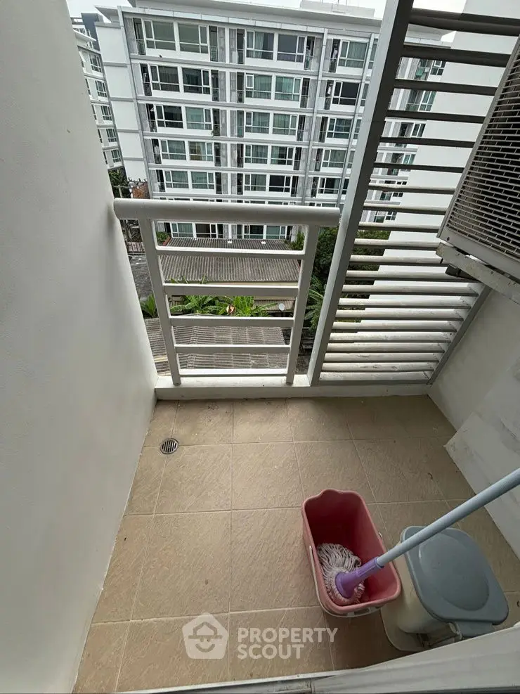 Compact balcony with city view in modern apartment building.
