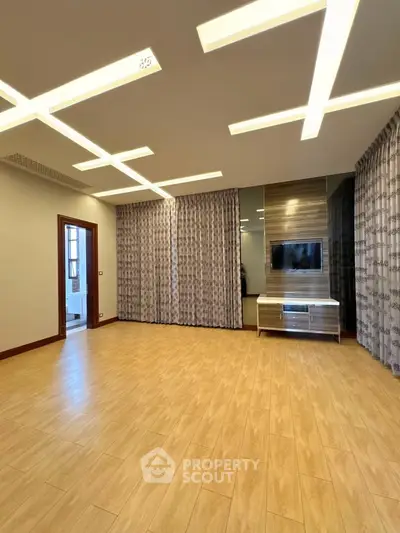 Spacious modern living room with stylish lighting and wooden flooring, perfect for family gatherings.