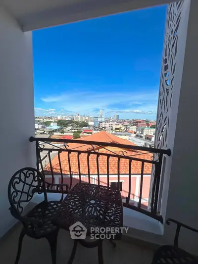 Charming balcony with intricate railing offering stunning cityscape views under a clear blue sky.