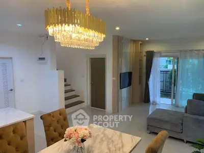 Elegant living room with chandelier and modern decor, featuring a cozy seating area and stylish staircase.