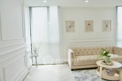 Elegant living room with beige tufted sofa, modern decor, and natural light through large windows.