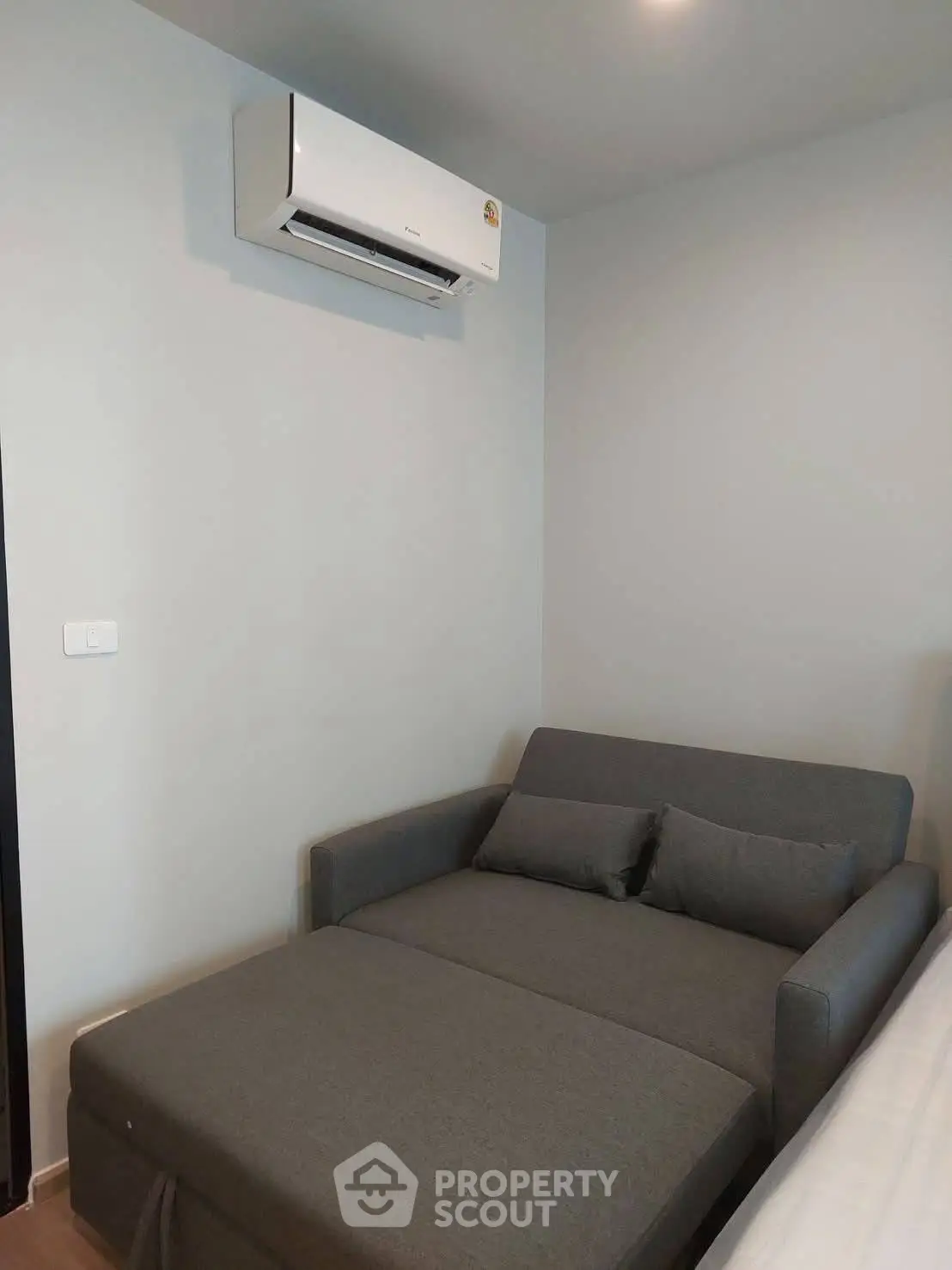 Cozy small living room with modern gray sofa and wall-mounted air conditioner, perfect for compact spaces.