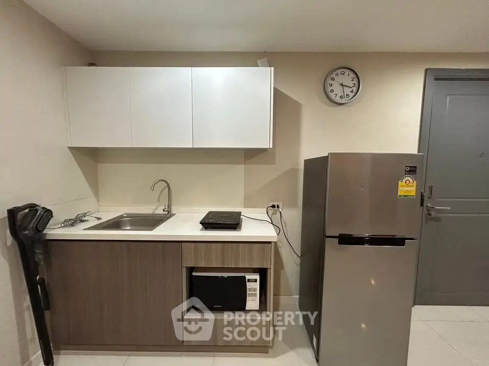 Modern kitchen with sleek cabinetry, stainless steel fridge, and compact appliances in a cozy apartment.